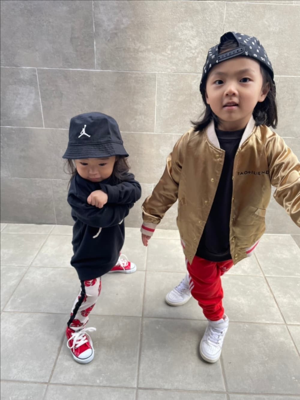 ゴールド系のスカジャン、レッド系のスウェットパンツ、ホワイト系のスニーカーを着用したキッズの春コーディネートの2枚目の写真