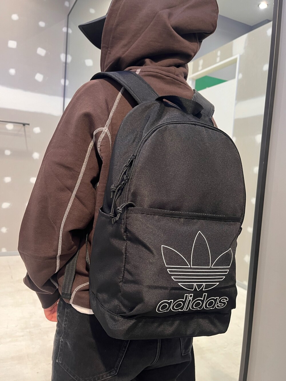 ブラック系のシューズ、ブラック系のバックパック/リュック、ブラウン系のパーカーを着用したレディースの冬コーディネートの3枚目の写真