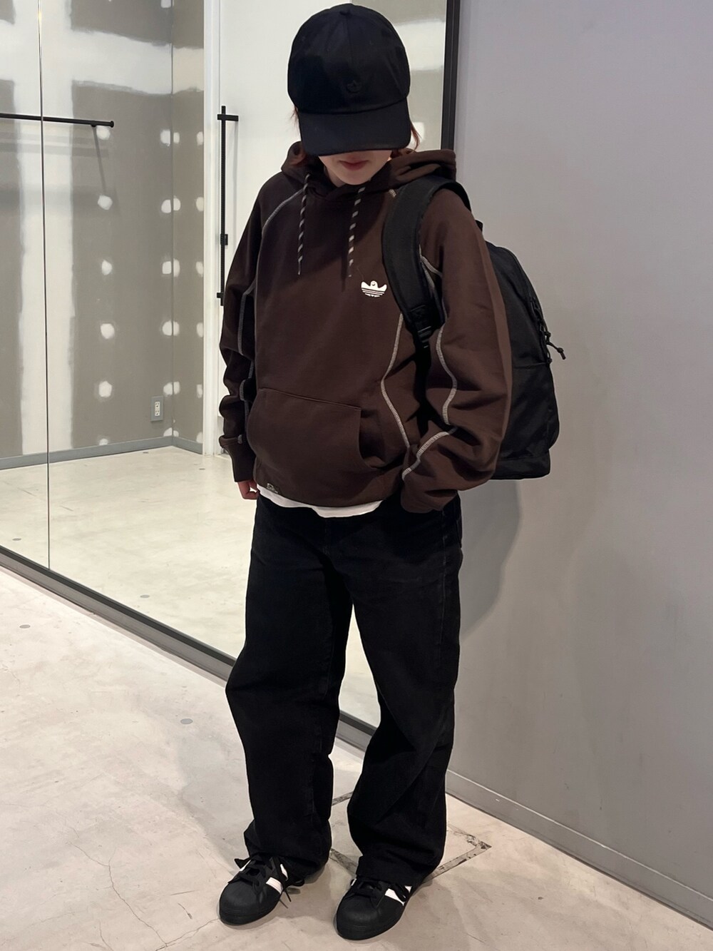 ブラック系のシューズ、ブラック系のバックパック/リュック、ブラウン系のパーカーを着用したレディースの冬コーディネートの2枚目の写真