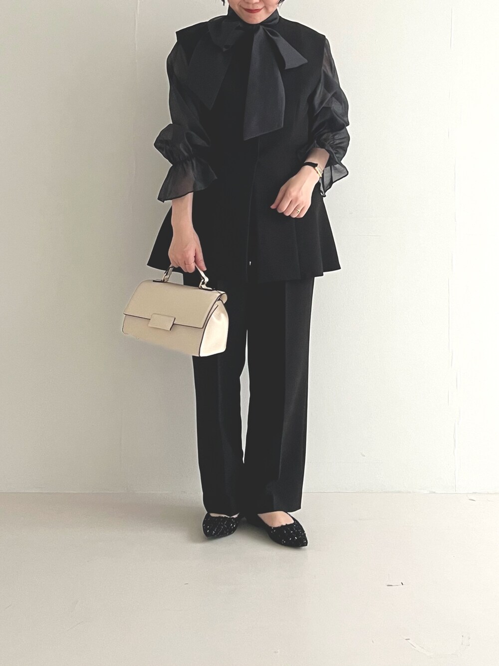ブラック系のセットアップ、ブラック系のパンプス、ホワイト系のショルダーバッグを着用したレディースの冬コーディネートの4枚目の写真