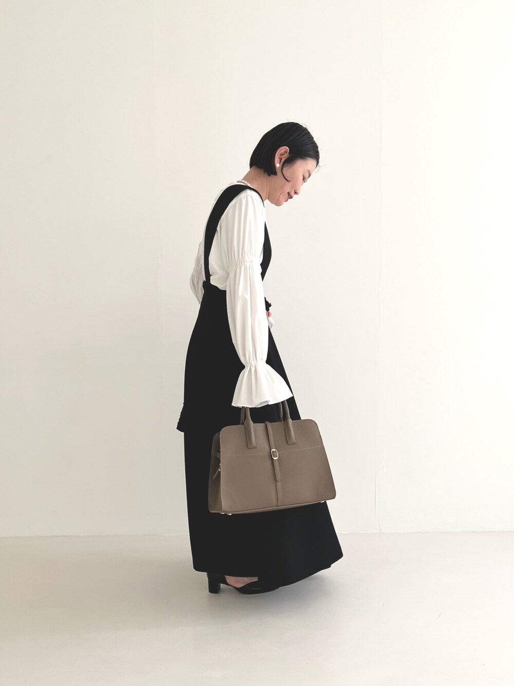 ブラック系のスカート、ホワイト系のシャツ/ブラウス、グレー系のハンドバッグを着用したレディースの冬コーディネートの4枚目の写真