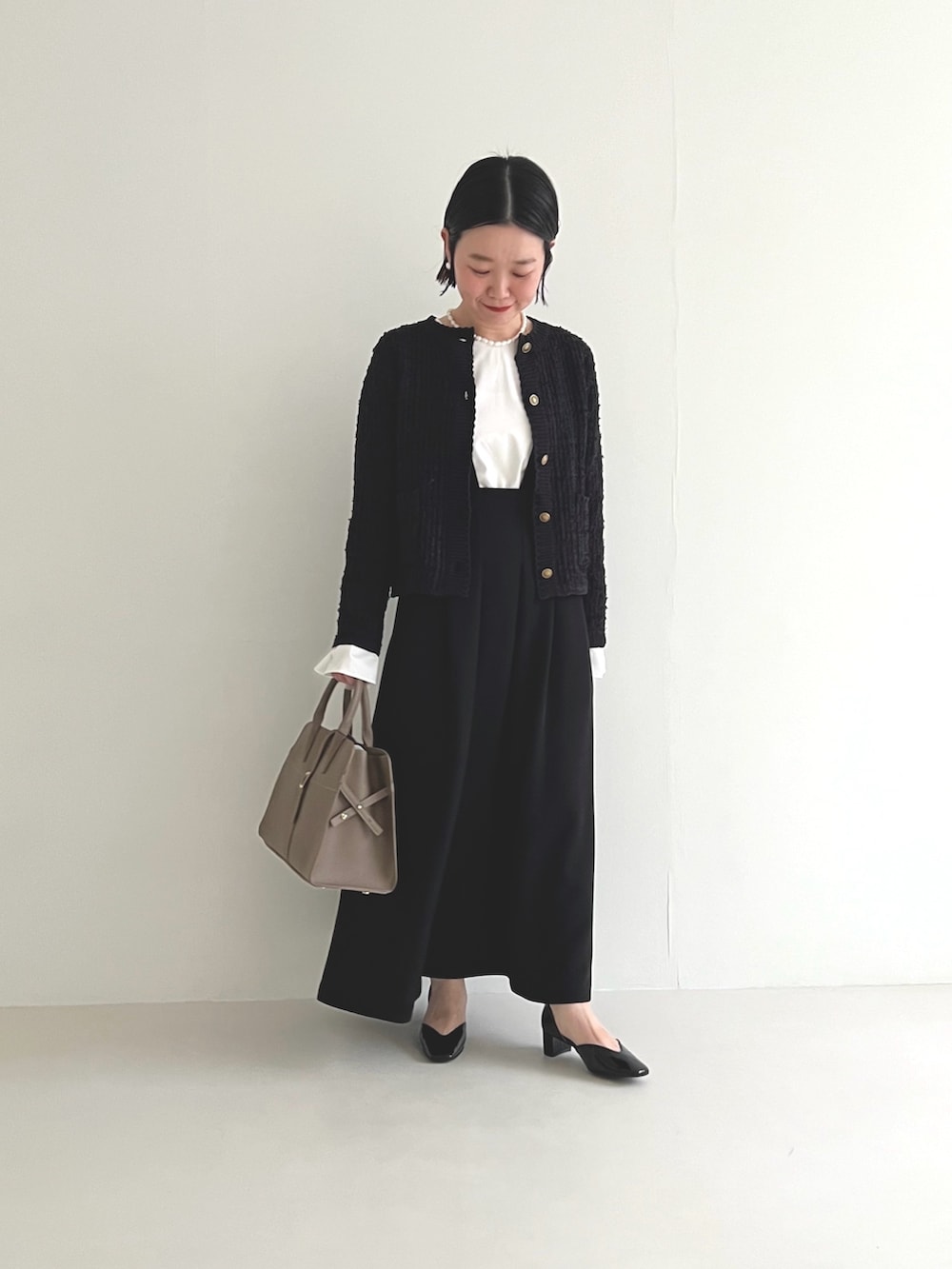 ブラック系のスカート、ホワイト系のシャツ/ブラウス、グレー系のハンドバッグを着用したレディースの冬コーディネートの2枚目の写真