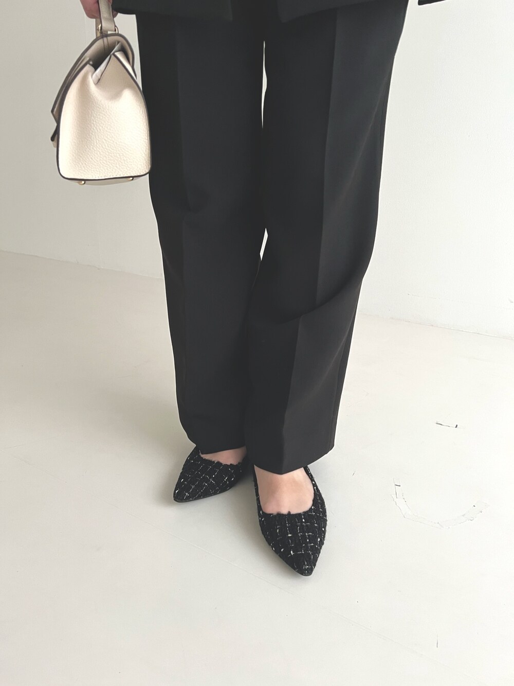 ブラック系のセットアップ、ブラック系のパンプス、ホワイト系のショルダーバッグを着用したレディースの冬コーディネートの3枚目の写真