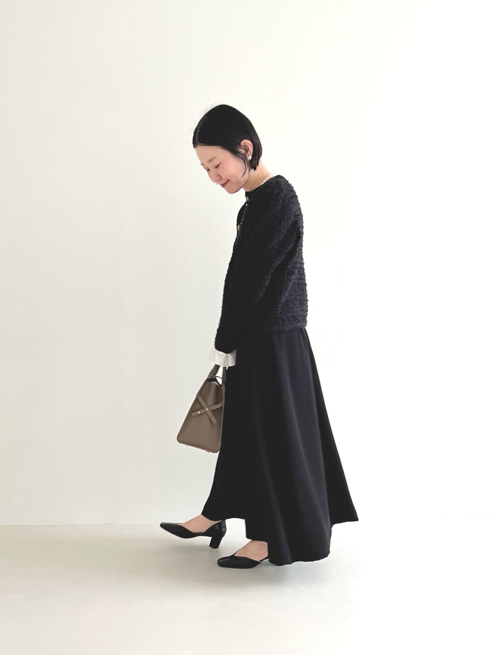 ブラック系のスカート、ホワイト系のシャツ/ブラウス、グレー系のハンドバッグを着用したレディースの冬コーディネートの3枚目の写真