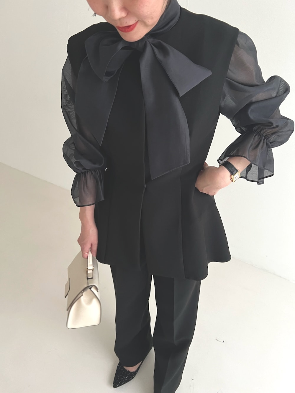 ブラック系のセットアップ、ブラック系のパンプス、ホワイト系のショルダーバッグを着用したレディースの冬コーディネートの2枚目の写真