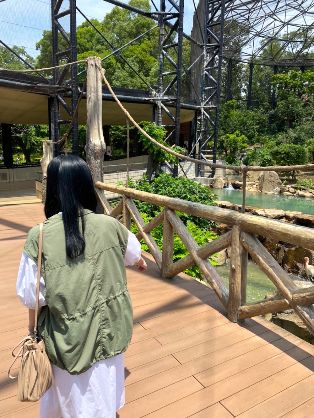 グリーン系のミリタリージャケット、ホワイト系のシャツワンピース、グリーン系のスニーカーを着用したレディースの夏コーディネートの3枚目の写真