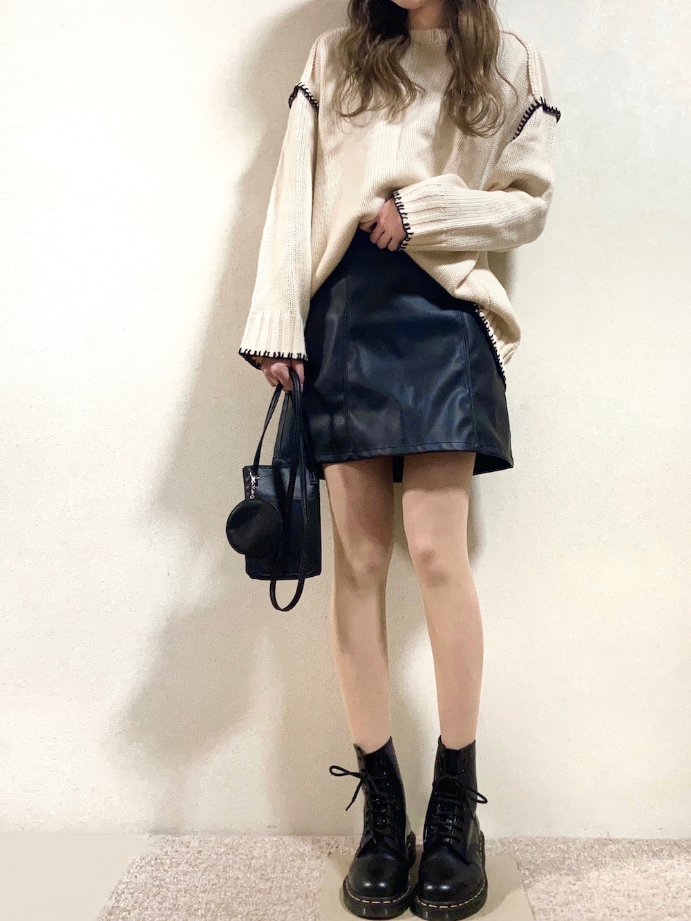 ホワイト系のニット/セーター、ブラック系のスカート、ブラック系のトートバッグを着用したレディースの春コーディネートの2枚目の写真