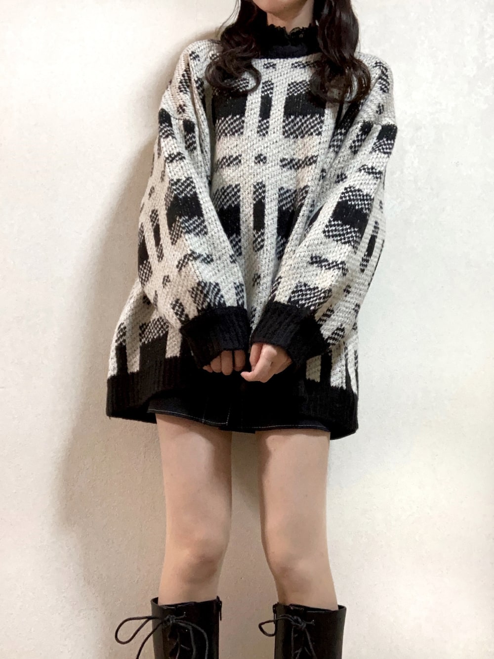 ブラック系のブーツ、ホワイト系のハンドバッグ、ブラック系のニット/セーターを着用したレディースの秋コーディネートの2枚目の写真