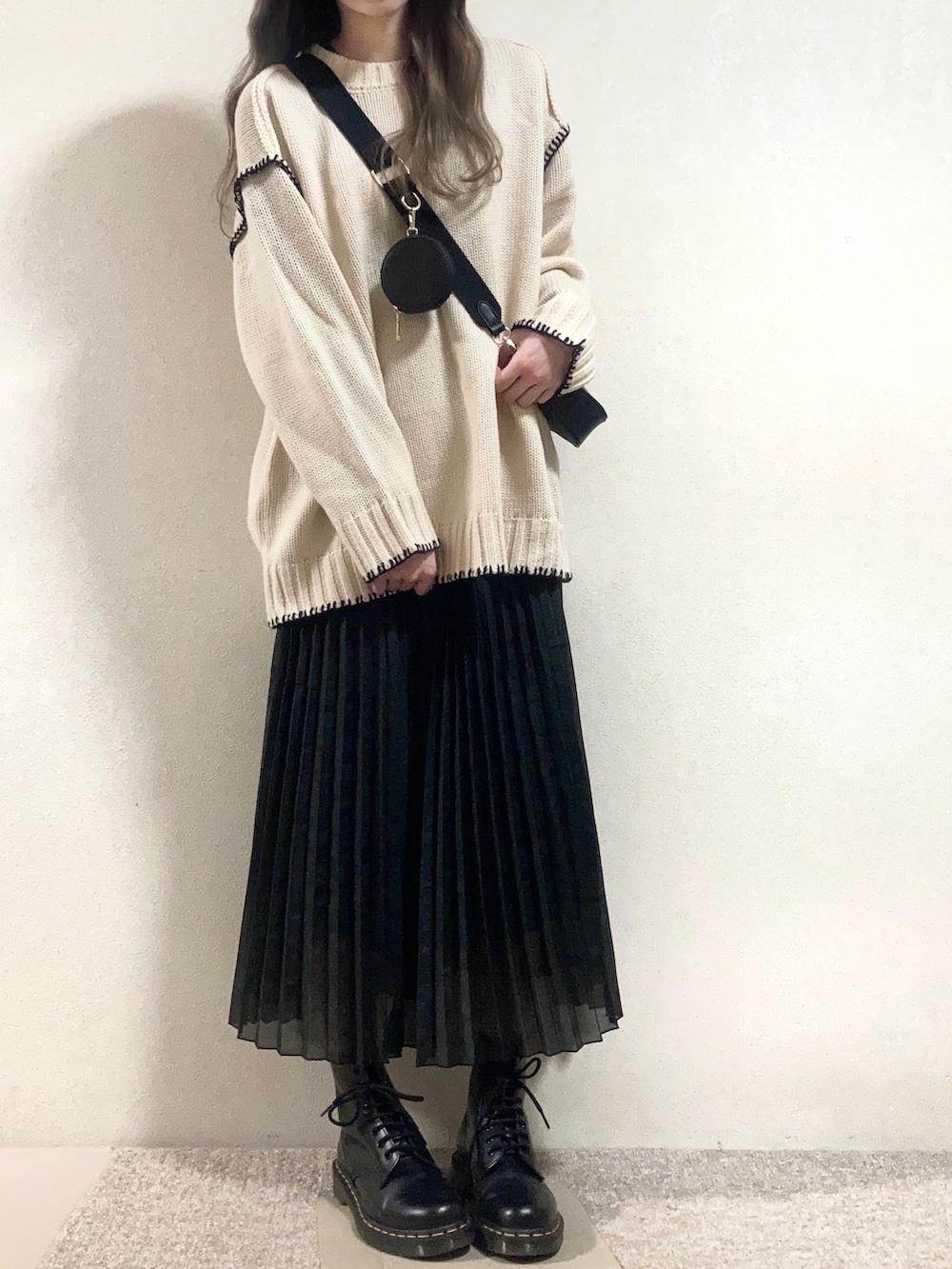 ブラック系のショルダーバッグ、ホワイト系のニット/セーター、ブラック系のスカートを着用したレディースの春コーディネートの3枚目の写真