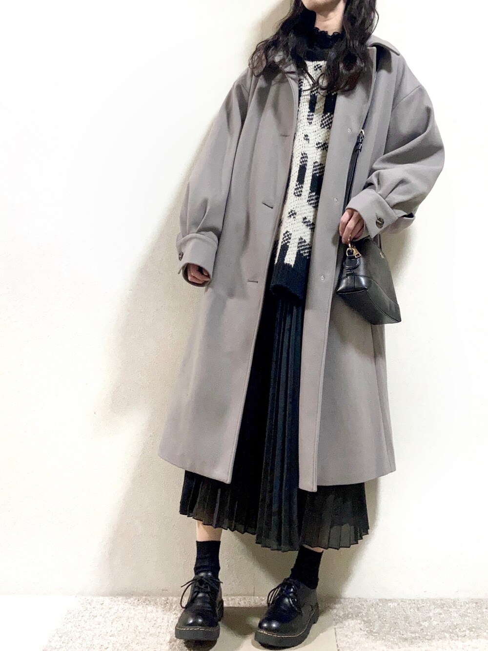 ベージュ系のステンカラーコート、ブラック系のニット/セーター、ブラック系のシャツ/ブラウスを着用したレディースの冬コーディネートの2枚目の写真