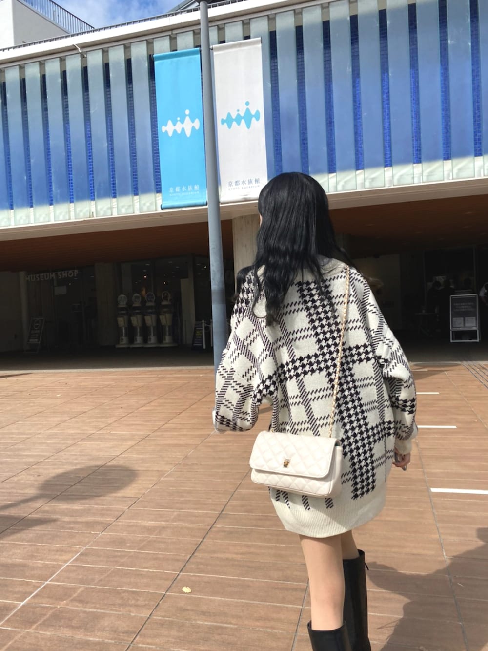 ブラック系のブーツ、ブラック系のスカート、ホワイト系のカーディガン/ボレロを着用したレディースの秋コーディネートの2枚目の写真