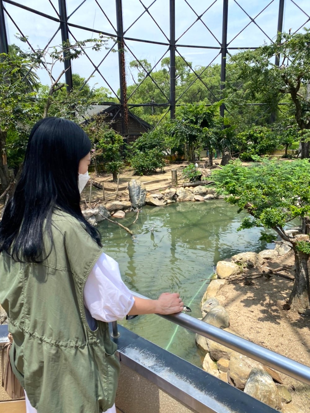 グリーン系のミリタリージャケット、ホワイト系のシャツワンピース、グリーン系のスニーカーを着用したレディースの夏コーディネートの2枚目の写真