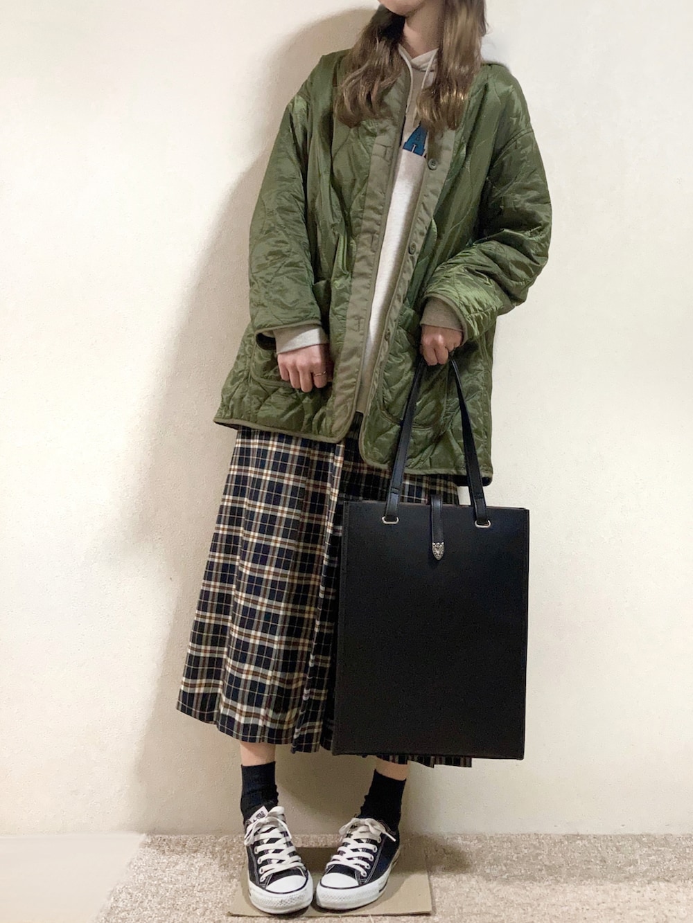 ホワイト系のパーカー、グリーン系のブルゾン、ブラック系のスカートを着用したレディースの春コーディネートの2枚目の写真