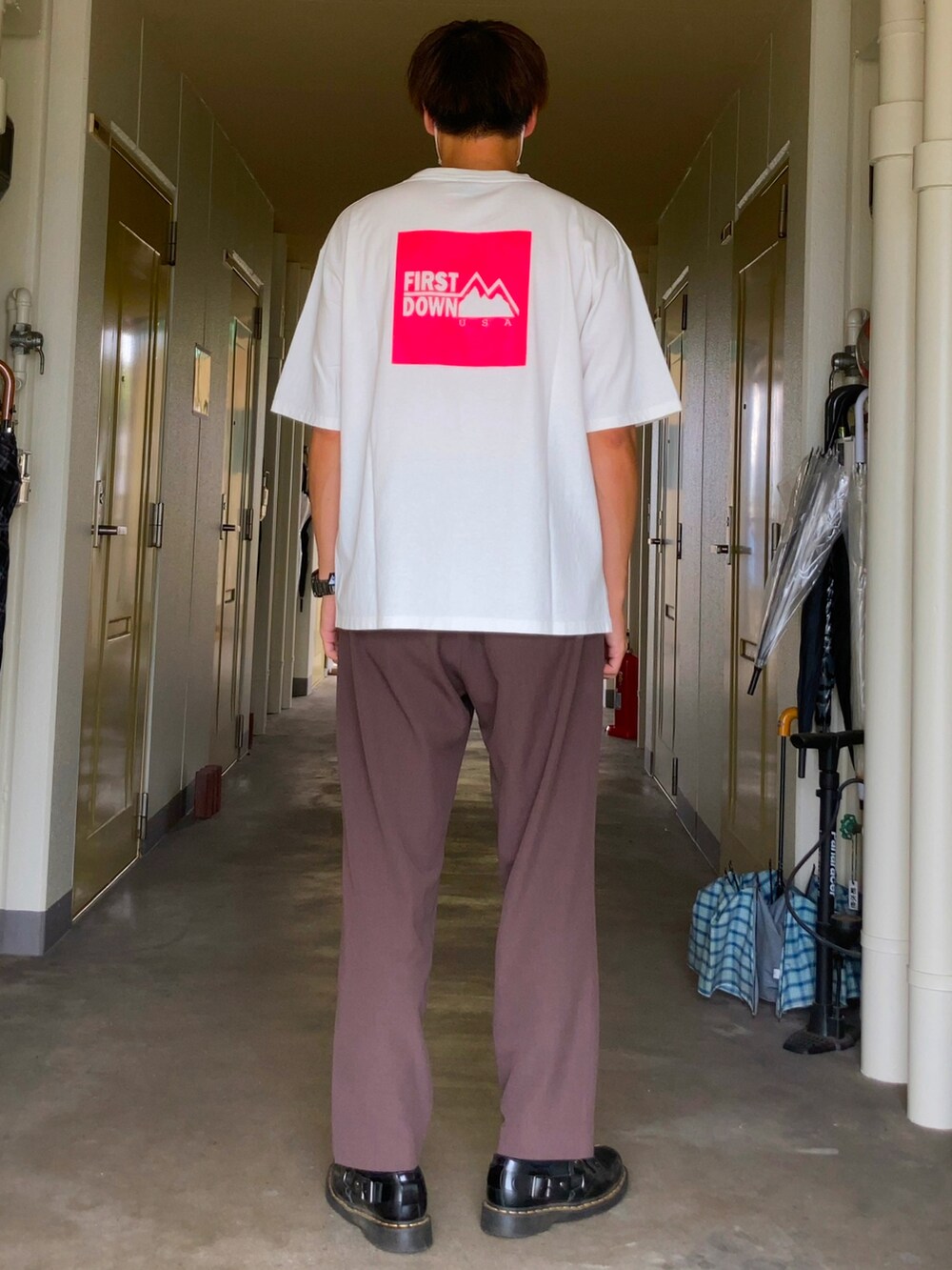 ブラウン系のスラックス、ブラック系のドレスシューズ、ホワイト系のTシャツ/カットソーを着用したメンズの夏コーディネートの2枚目の写真