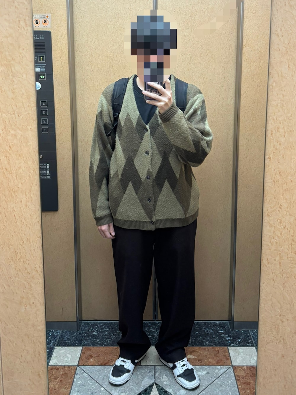 ブラウン系のカーディガン/ボレロ、ブラック系のTシャツ/カットソー、ブラック系のスニーカーを着用したメンズの秋コーディネートの2枚目の写真