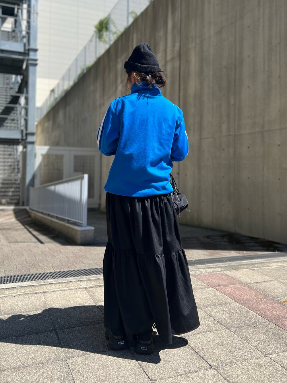 ブラック系のスニーカー、ブラック系のスカート、ブルー系のジャージを着用したレディースの夏コーディネートの2枚目の写真