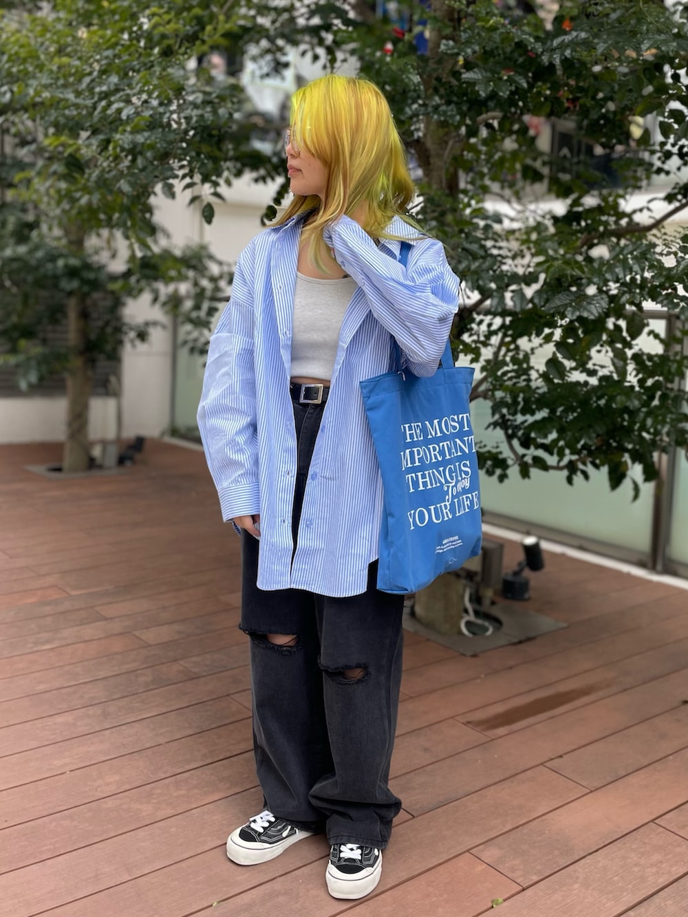 ブラック系のデニムパンツ、ブルー系のシャツ/ブラウス、ブルー系のトートバッグを着用したレディースの春コーディネートの2枚目の写真