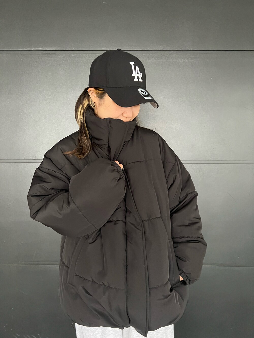 ブラック系のスニーカー、ベージュ系のスウェットパンツ、ブラック系のダウンジャケット/コートを着用したレディースの冬コーディネートの2枚目の写真