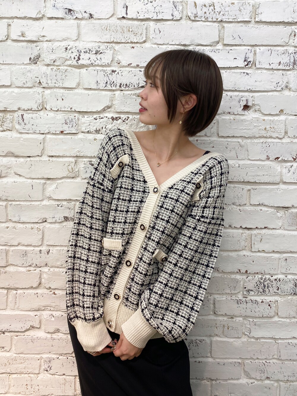 ホワイト系のカーディガン/ボレロ、ブラック系のジャンパースカートを着用したレディースの秋コーディネートの2枚目の写真