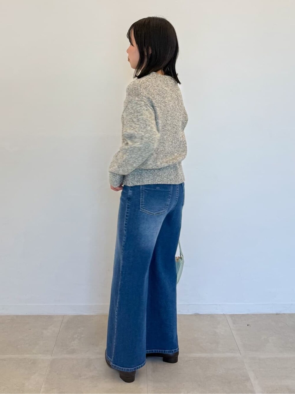 イエロー系のニット/セーター、ブルー系のデニムパンツ、グリーン系のショルダーバッグを着用したレディースの春コーディネートの4枚目の写真