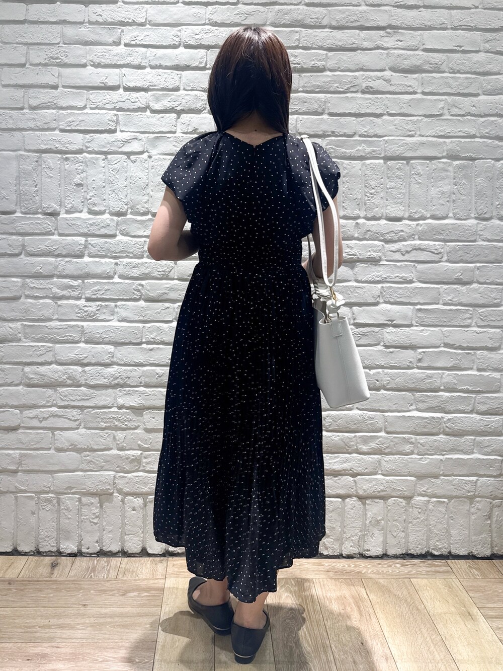 ブラック系のワンピース、ホワイト系のショルダーバッグ、ブラック系のパンプスを着用したレディースの春コーディネートの3枚目の写真