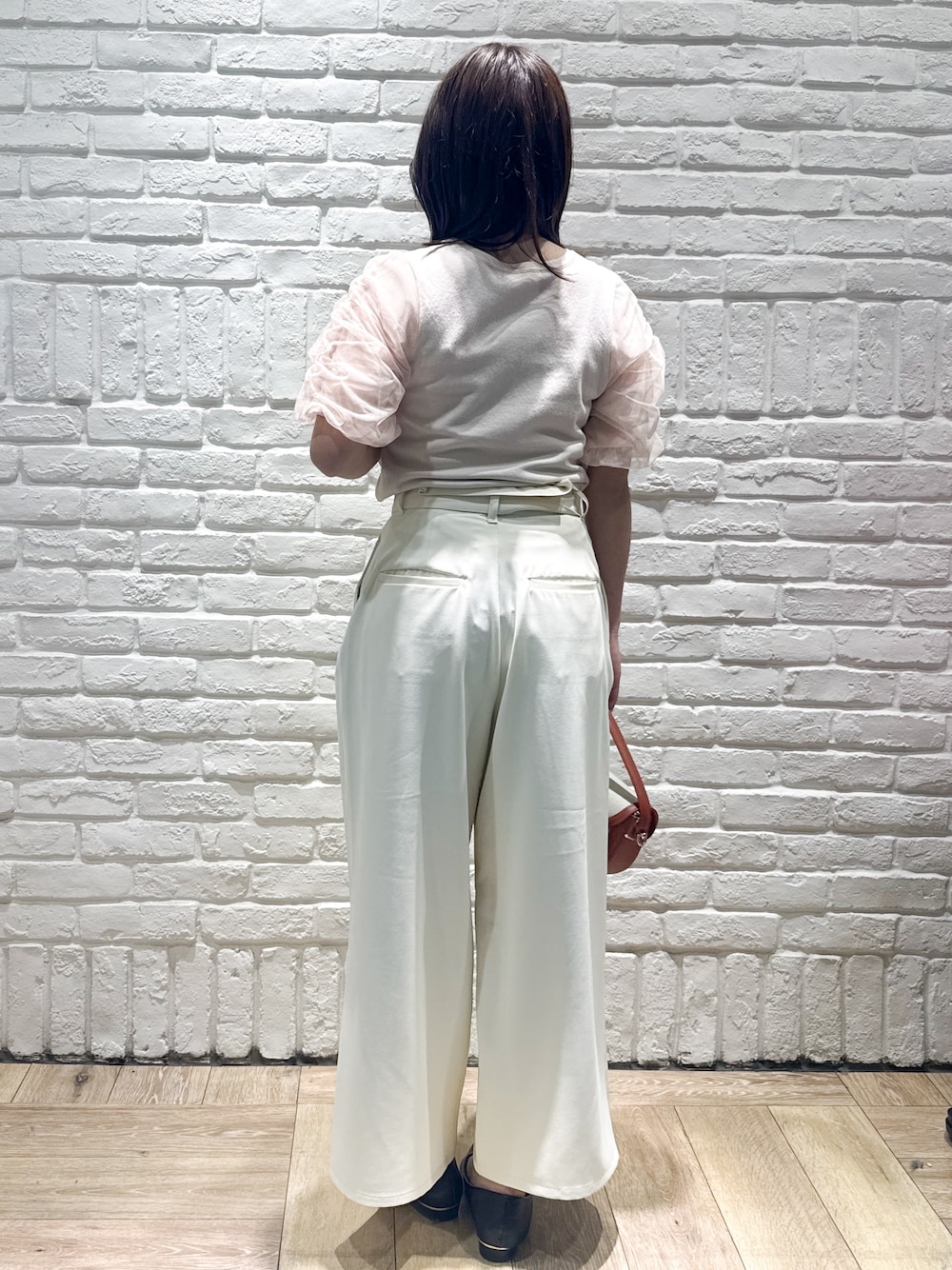 オレンジ系のニット/セーター、ホワイト系のその他パンツ、レッド系のショルダーバッグを着用したレディースの春コーディネートの3枚目の写真