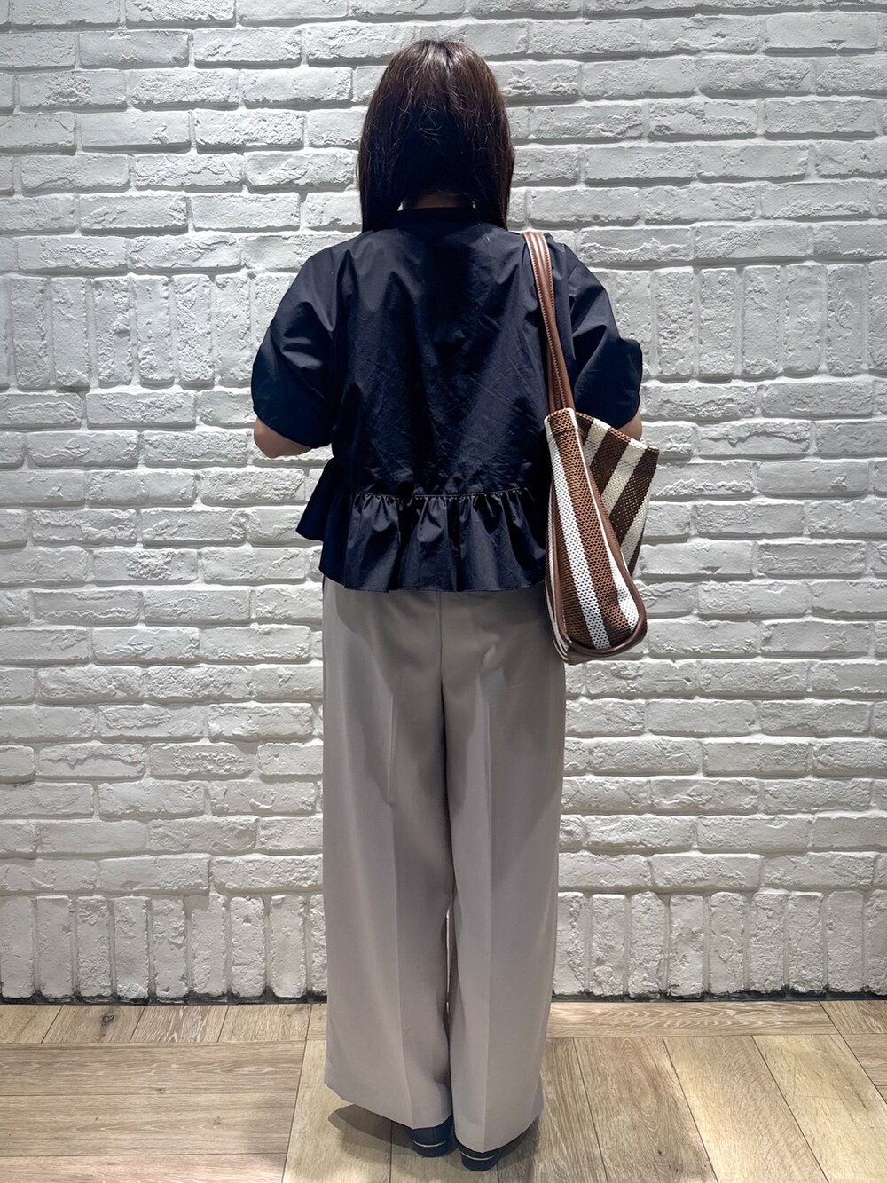 ブラック系のシャツ/ブラウス、ベージュ系のその他パンツ、ブラウン系のトートバッグを着用したレディースの春コーディネートの3枚目の写真