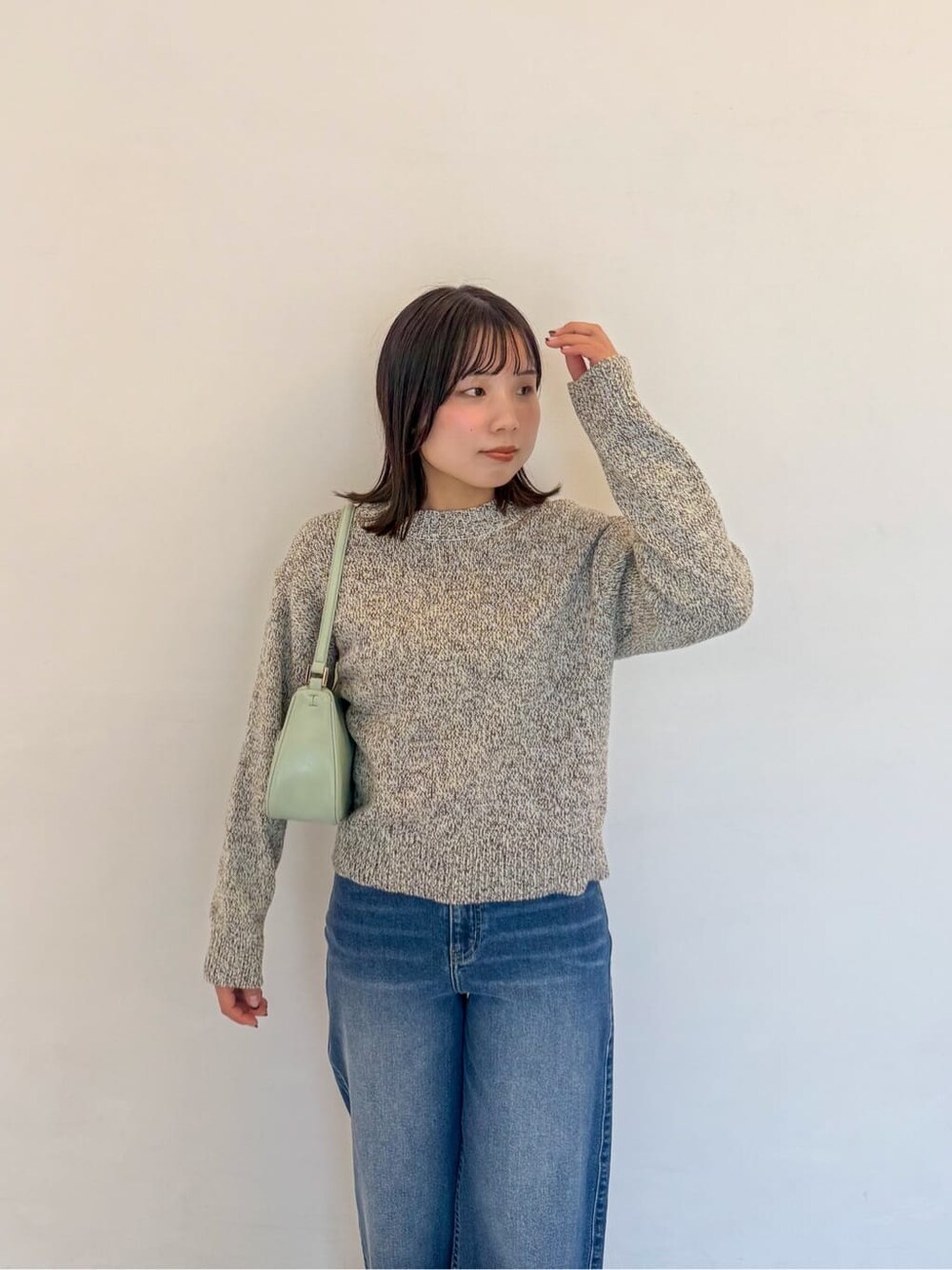 イエロー系のニット/セーター、ブルー系のデニムパンツ、グリーン系のショルダーバッグを着用したレディースの春コーディネートの5枚目の写真