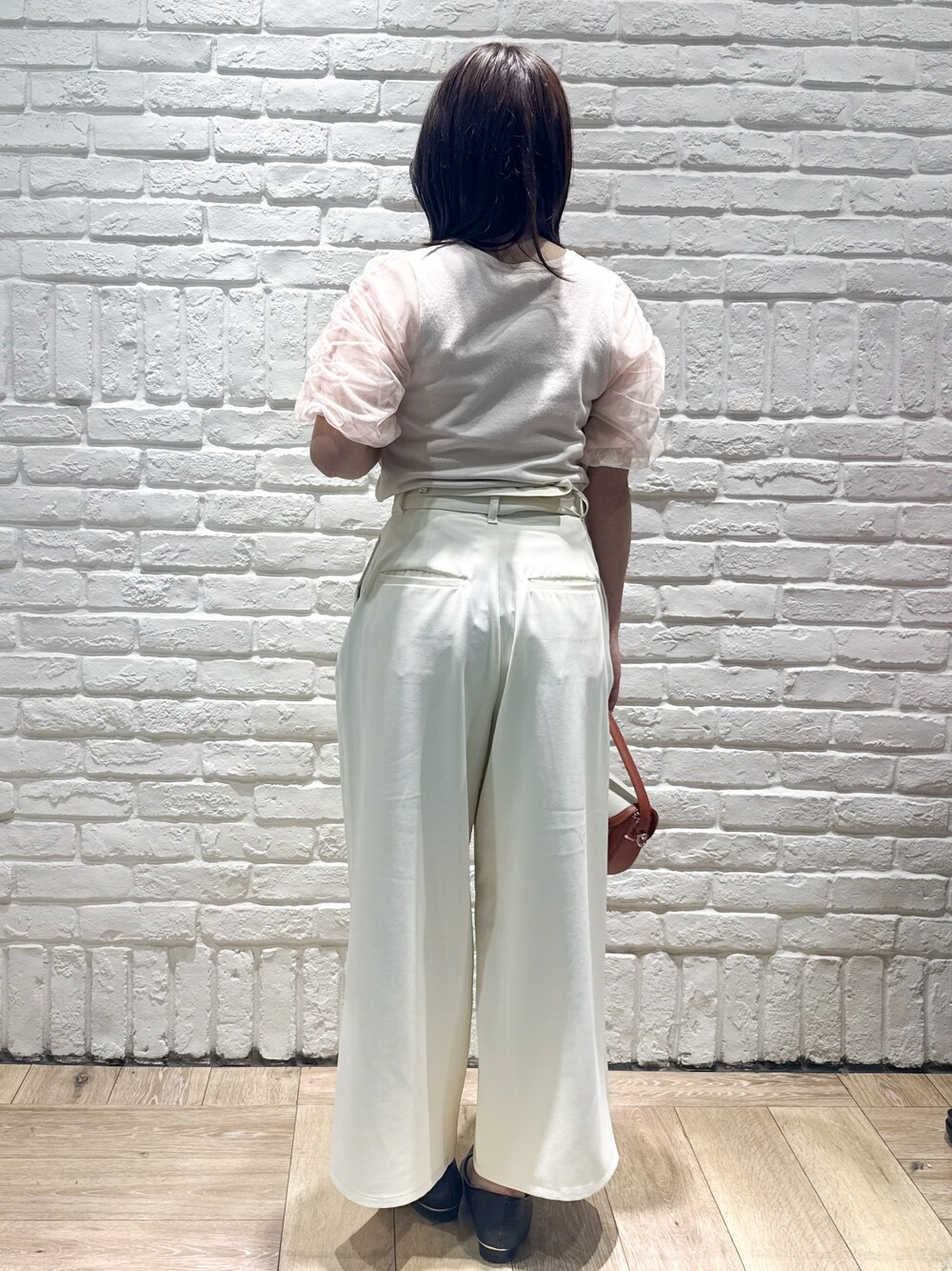 ブラック系のパンプス、レッド系のショルダーバッグ、オレンジ系のニット/セーターを着用したレディースの春コーディネートの3枚目の写真