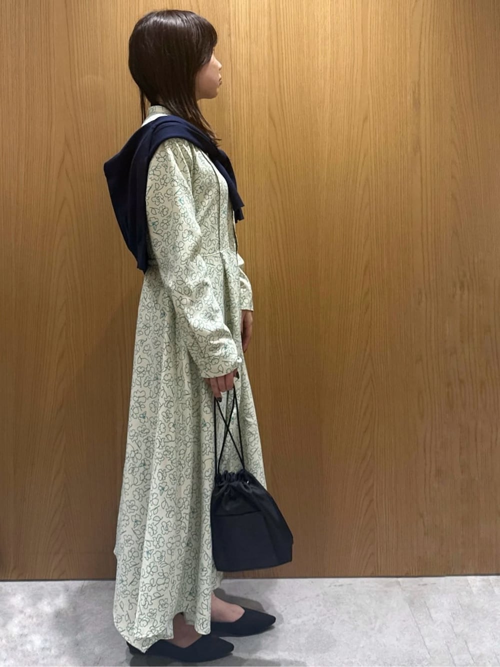 ベージュ系のワンピース、ブルー系のカーディガン/ボレロ、ブラック系のショルダーバッグを着用したレディースの春コーディネートの2枚目の写真