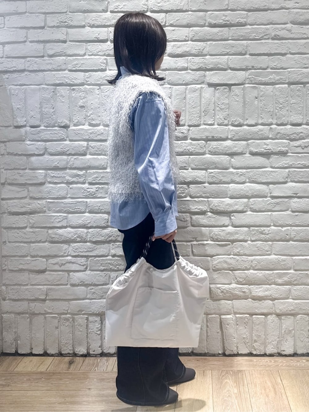 グレー系のニット/セーター、ブルー系のシャツ/ブラウス、ブルー系のデニムパンツを着用したレディースの春コーディネートの2枚目の写真