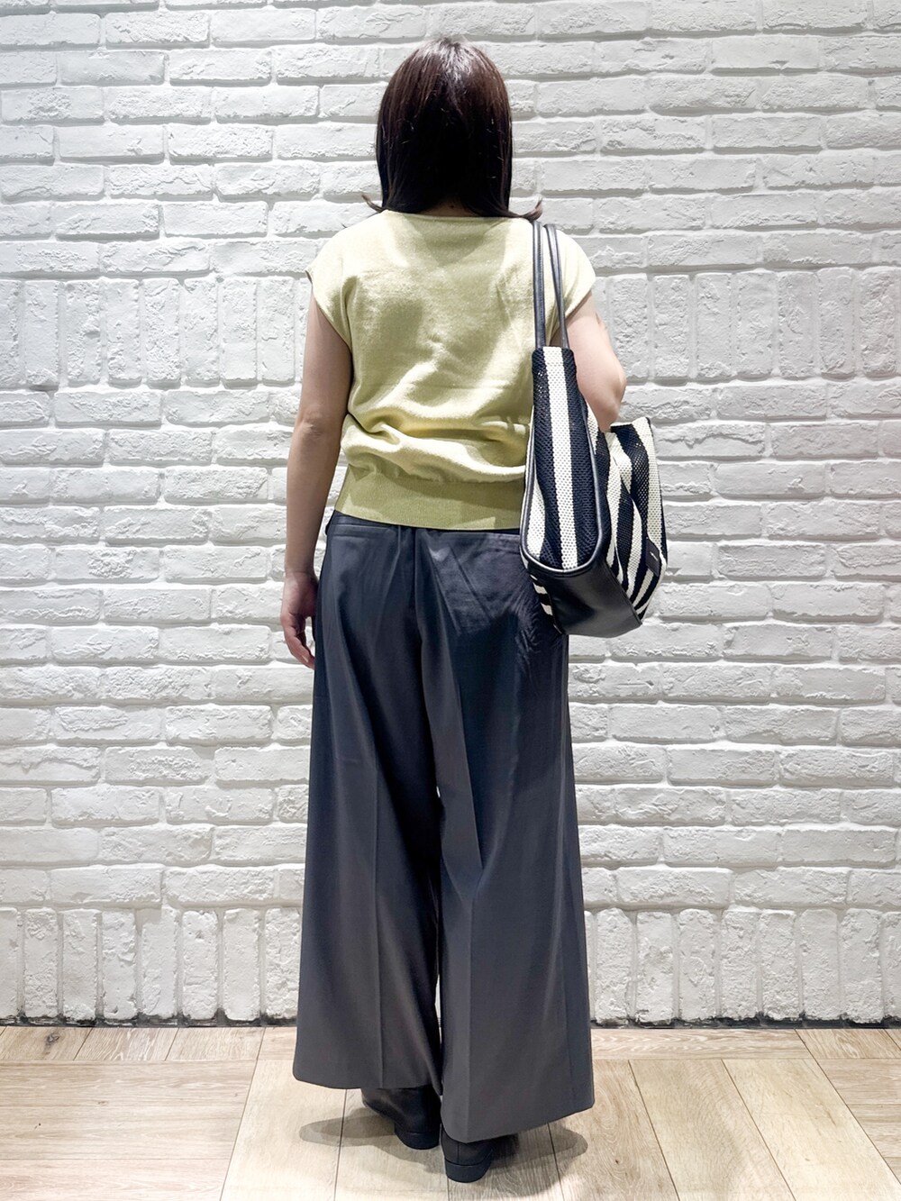イエロー系のニット/セーター、グレー系のその他パンツ、ブラック系のトートバッグを着用したレディースの夏コーディネートの3枚目の写真
