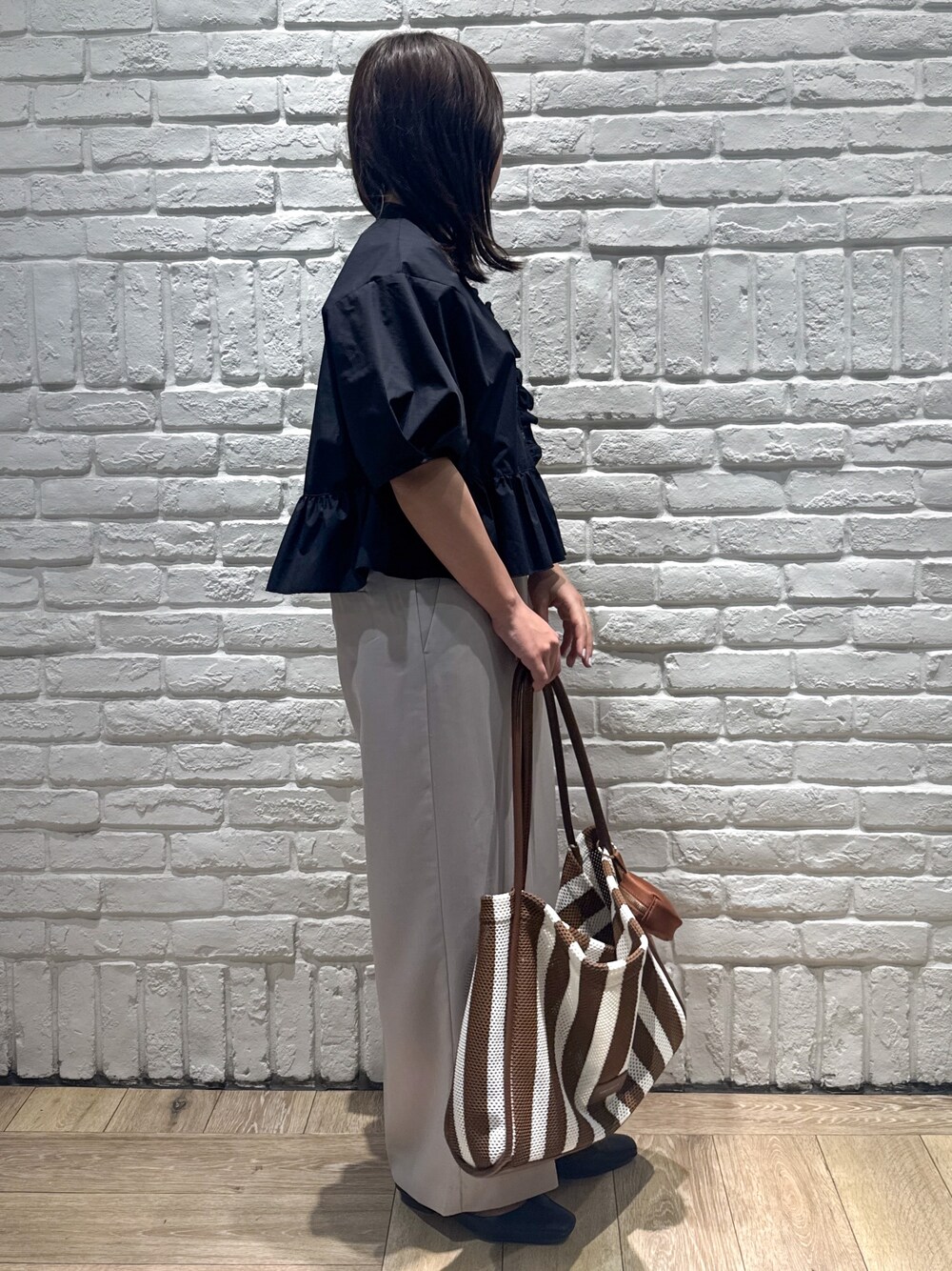 ブラック系のシャツ/ブラウス、ベージュ系のその他パンツ、ブラウン系のトートバッグを着用したレディースの春コーディネートの2枚目の写真