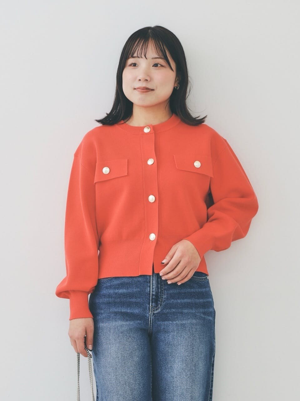 オレンジ系のカーディガン/ボレロ、ブルー系のデニムパンツ、グレー系のショルダーバッグを着用したレディースの冬コーディネートの6枚目の写真