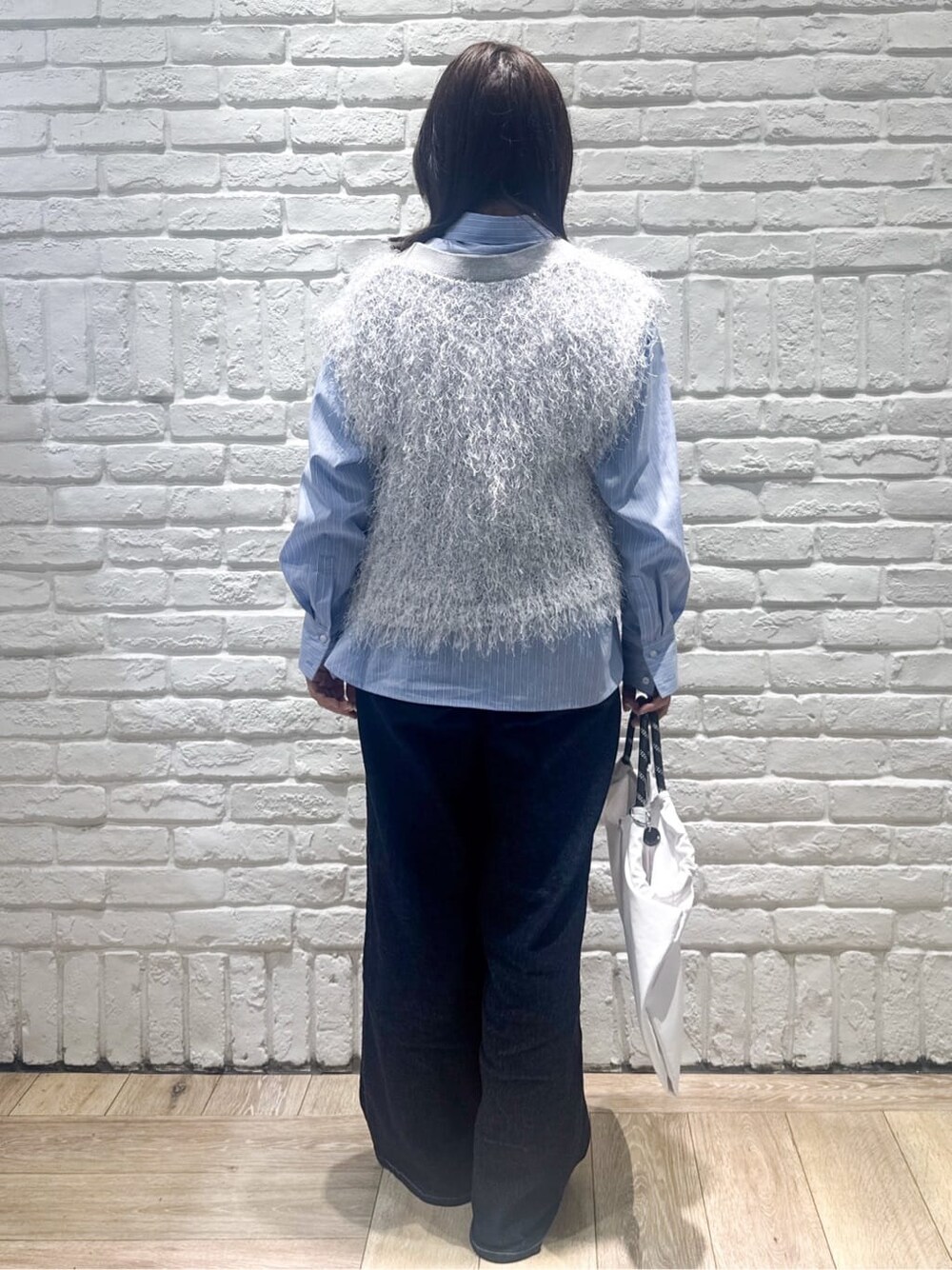 グレー系のニット/セーター、ブルー系のシャツ/ブラウス、ブルー系のデニムパンツを着用したレディースの春コーディネートの3枚目の写真