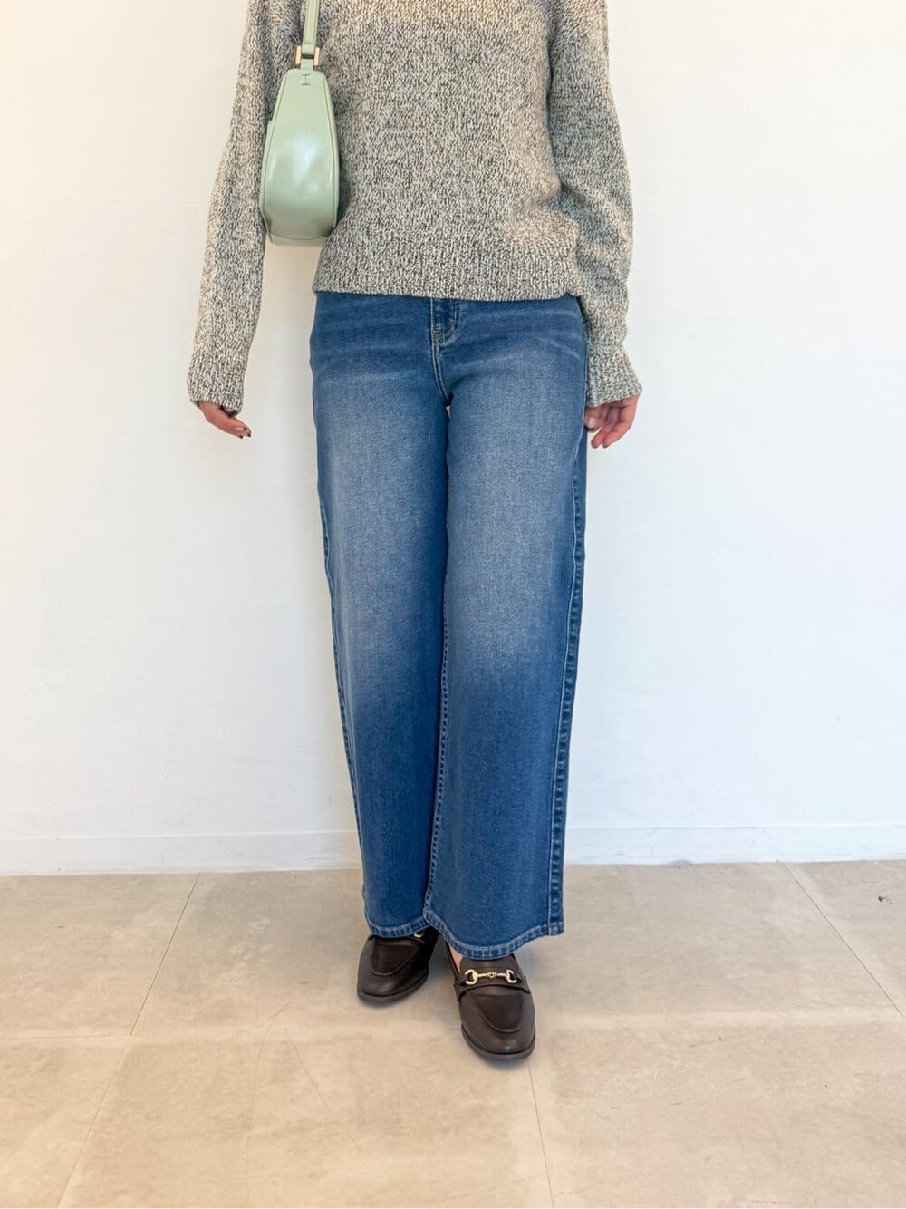 イエロー系のニット/セーター、ブルー系のデニムパンツ、グリーン系のショルダーバッグを着用したレディースの春コーディネートの6枚目の写真