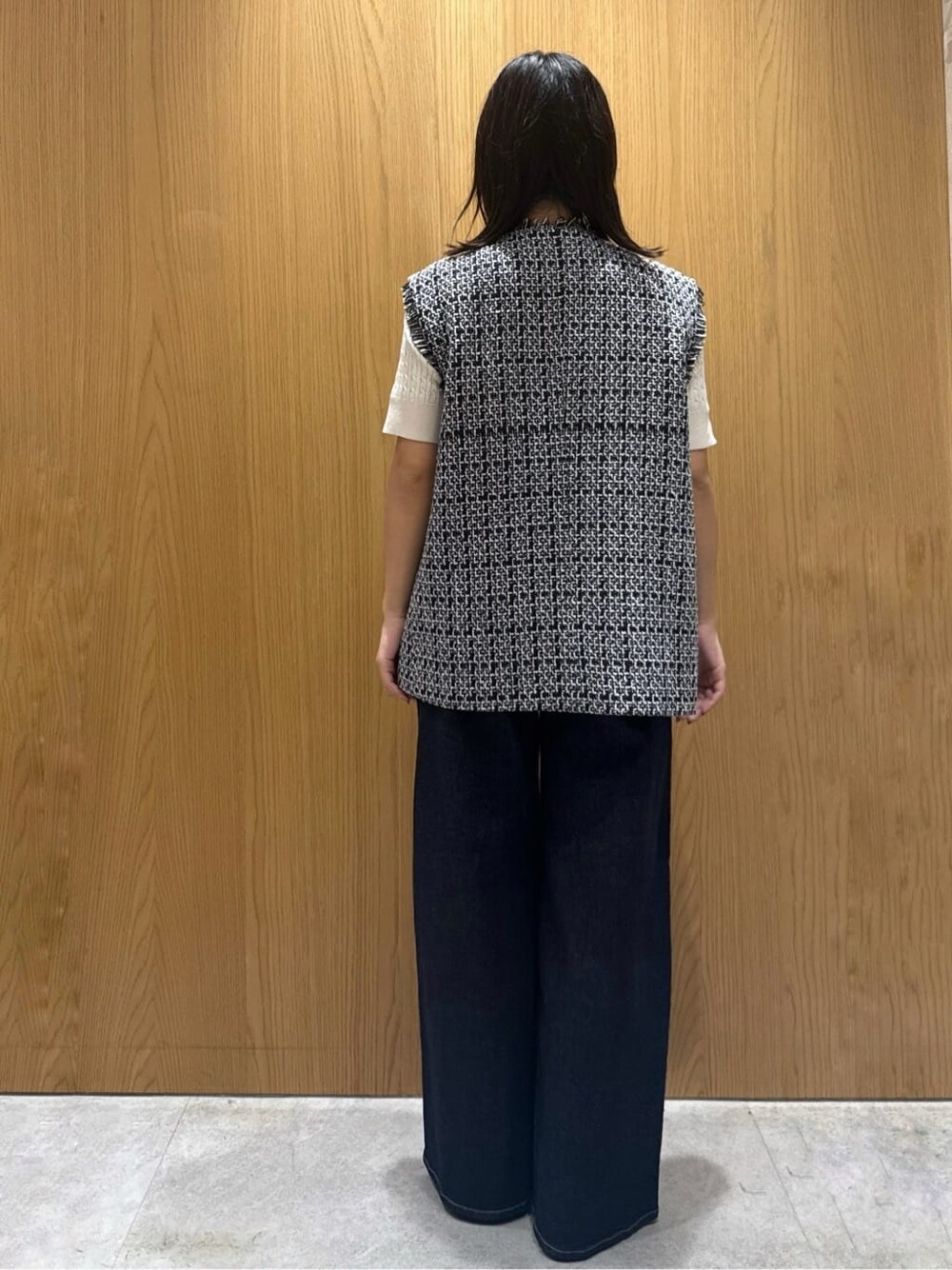 ブラック系のベスト、ホワイト系のニット/セーター、ブルー系のデニムパンツを着用したレディースの秋コーディネートの3枚目の写真