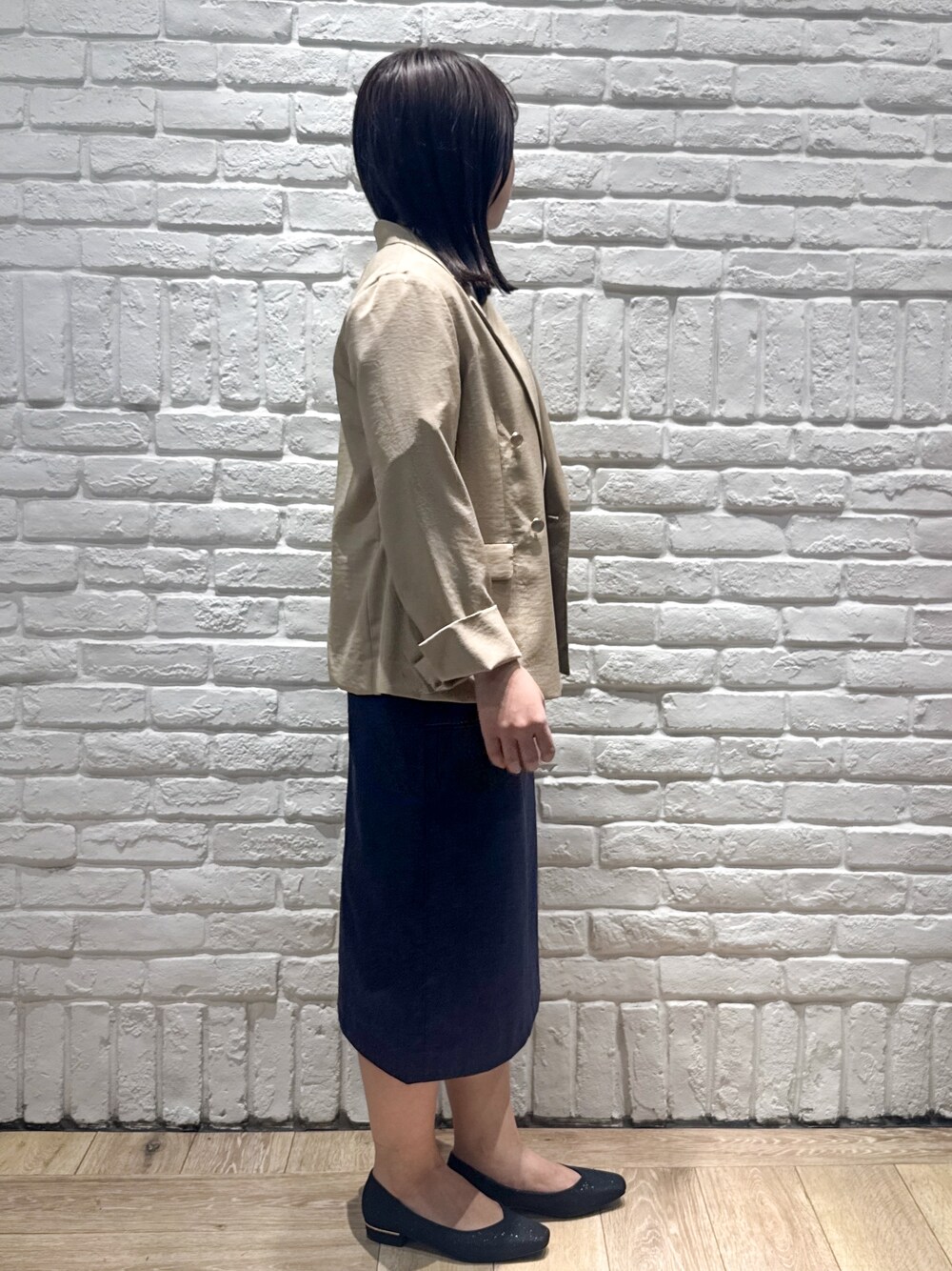 ベージュ系のテーラードジャケット、ホワイト系のTシャツ/カットソー、ブルー系のスカートを着用したレディースの春コーディネートの2枚目の写真