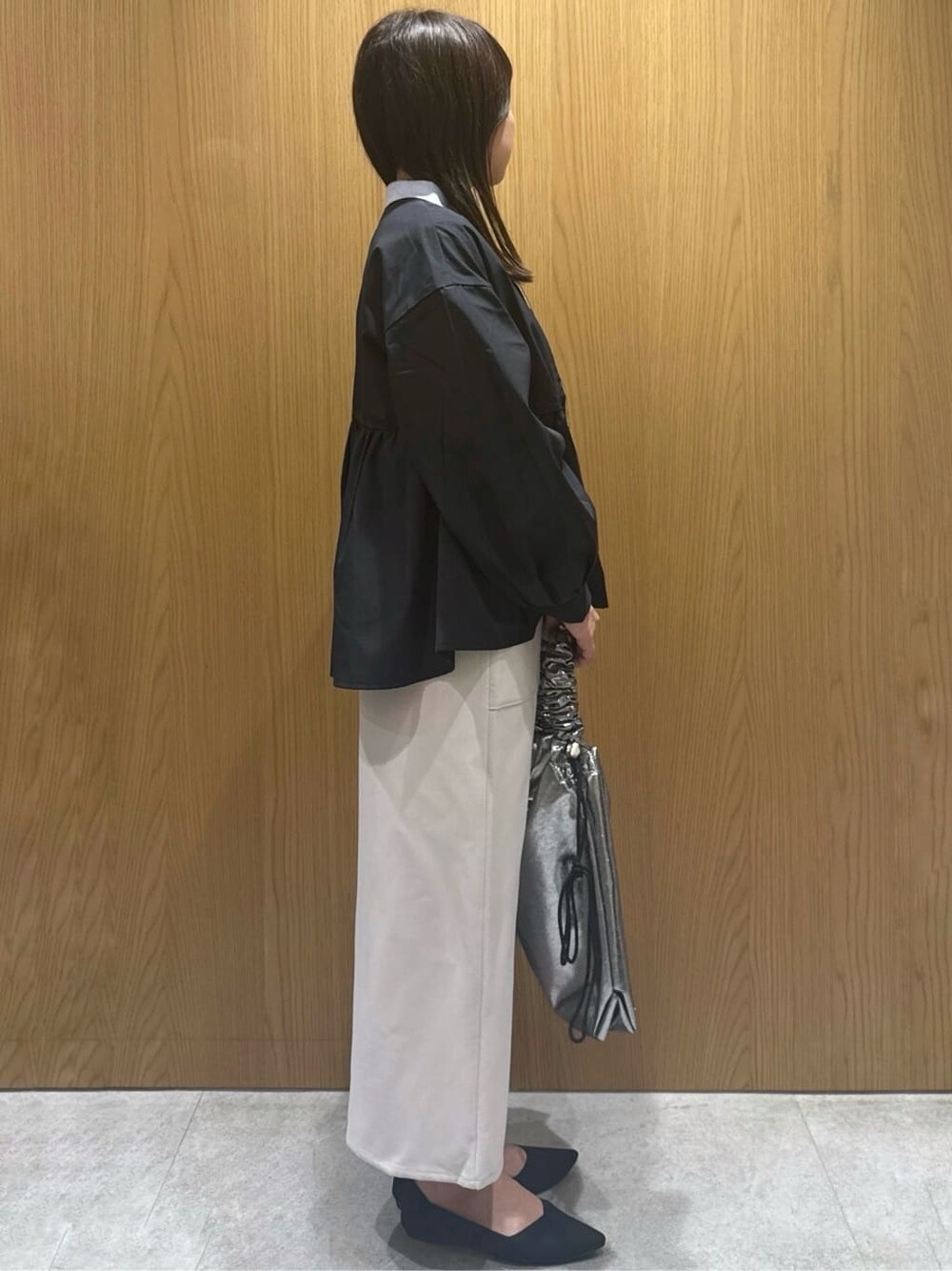 ブラック系のノーカラージャケット、ブルー系のニット/セーター、ベージュ系のスカートを着用したレディースの春コーディネートの2枚目の写真
