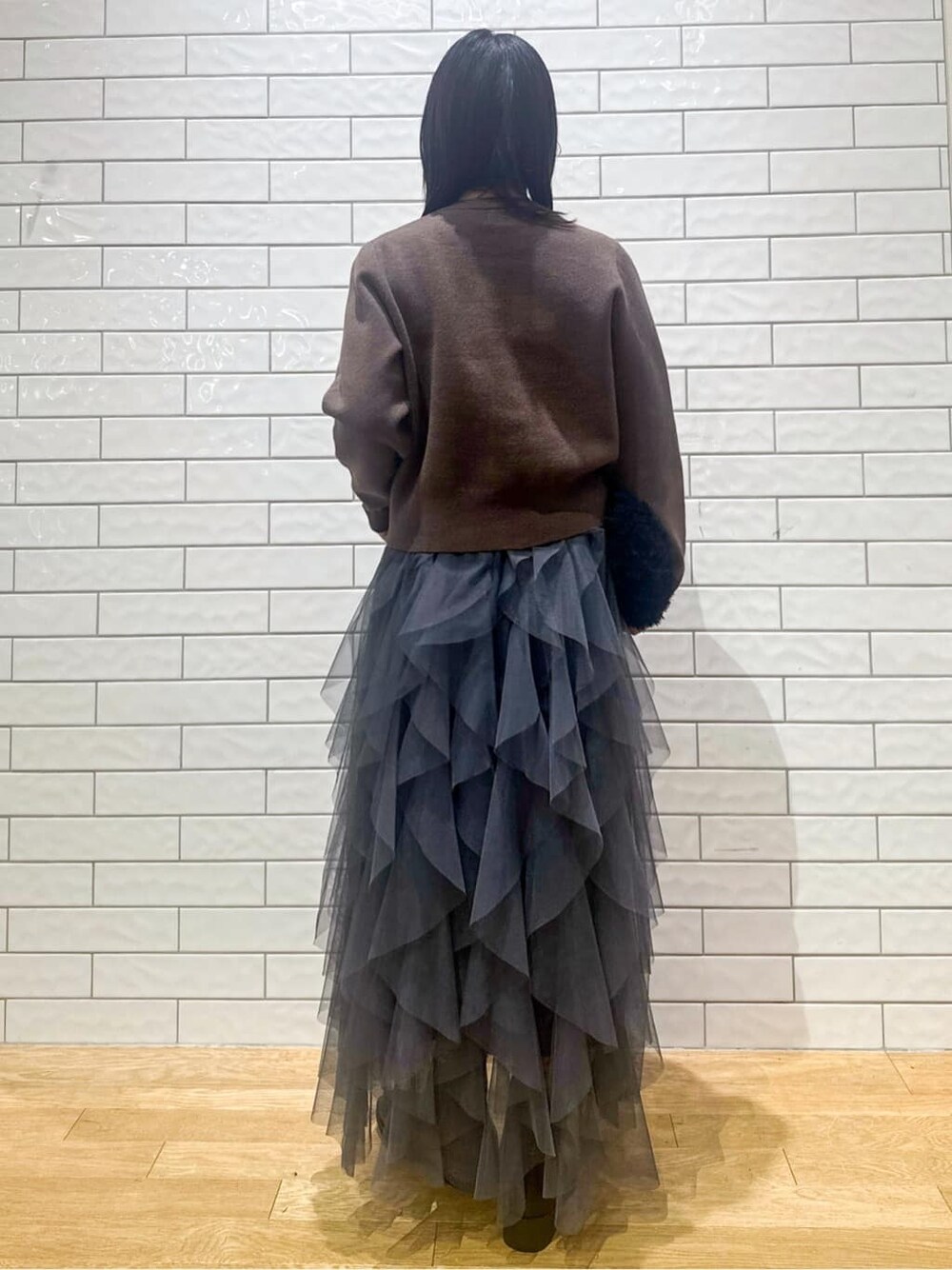 ブラウン系のカーディガン/ボレロ、グレー系のスカート、ブラック系のハンドバッグを着用したレディースの秋コーディネートの3枚目の写真