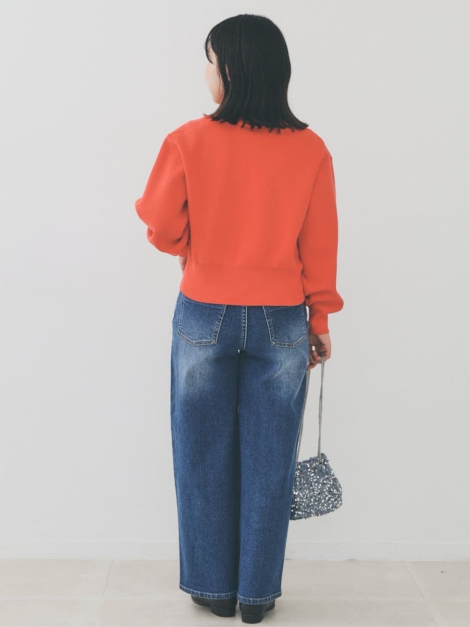 オレンジ系のカーディガン/ボレロ、ブルー系のデニムパンツ、グレー系のショルダーバッグを着用したレディースの冬コーディネートの4枚目の写真