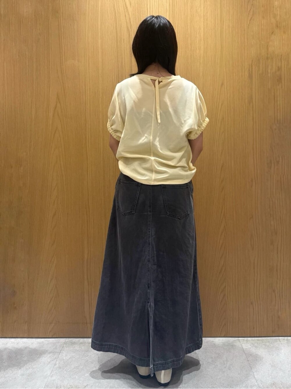 イエロー系のTシャツ/カットソー、ブラック系のデニムスカート、ベージュ系のショルダーバッグを着用したレディースの夏コーディネートの3枚目の写真