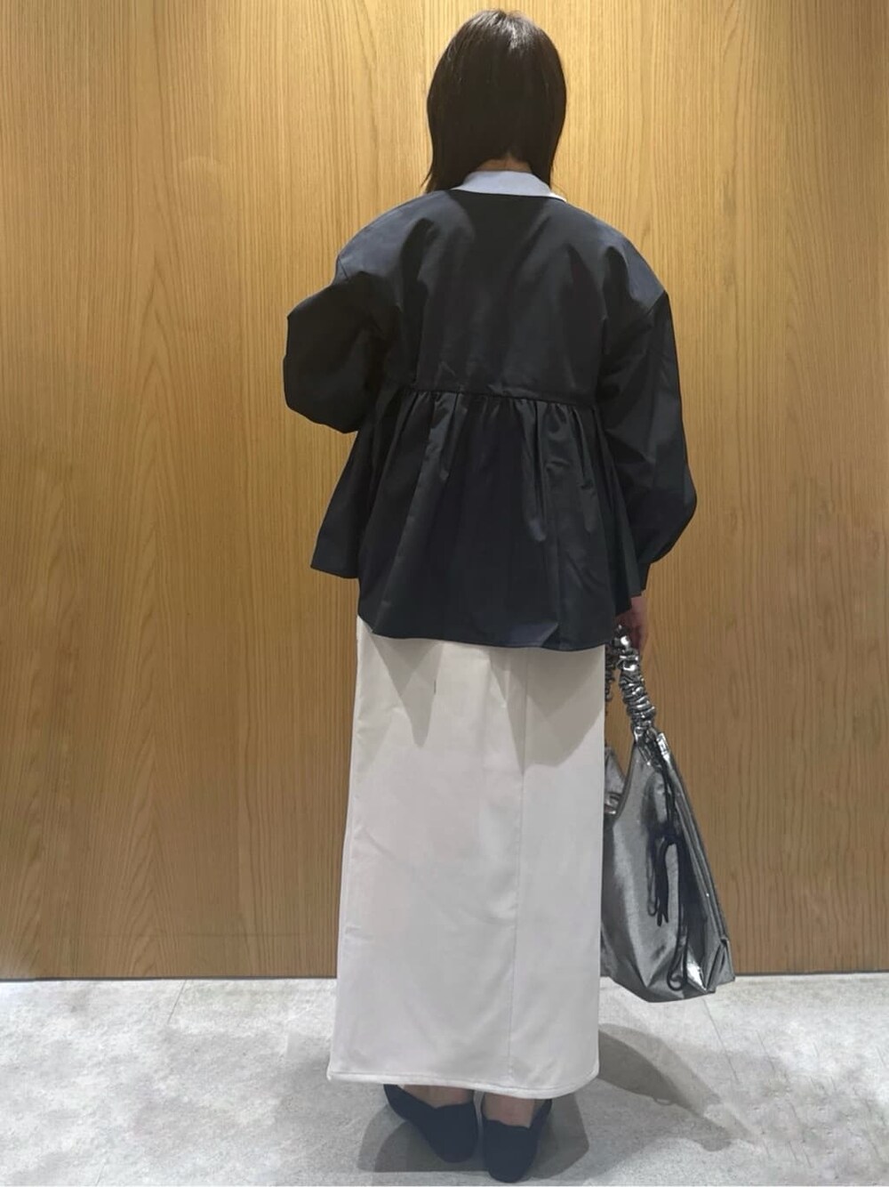 ブラック系のノーカラージャケット、ブルー系のニット/セーター、ベージュ系のスカートを着用したレディースの春コーディネートの3枚目の写真