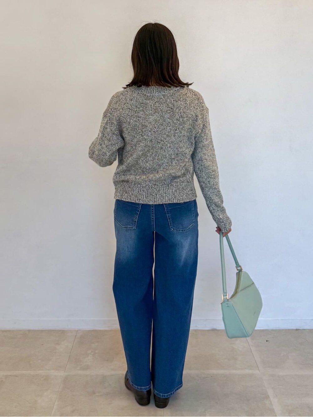 イエロー系のニット/セーター、ブルー系のデニムパンツ、グリーン系のショルダーバッグを着用したレディースの春コーディネートの3枚目の写真