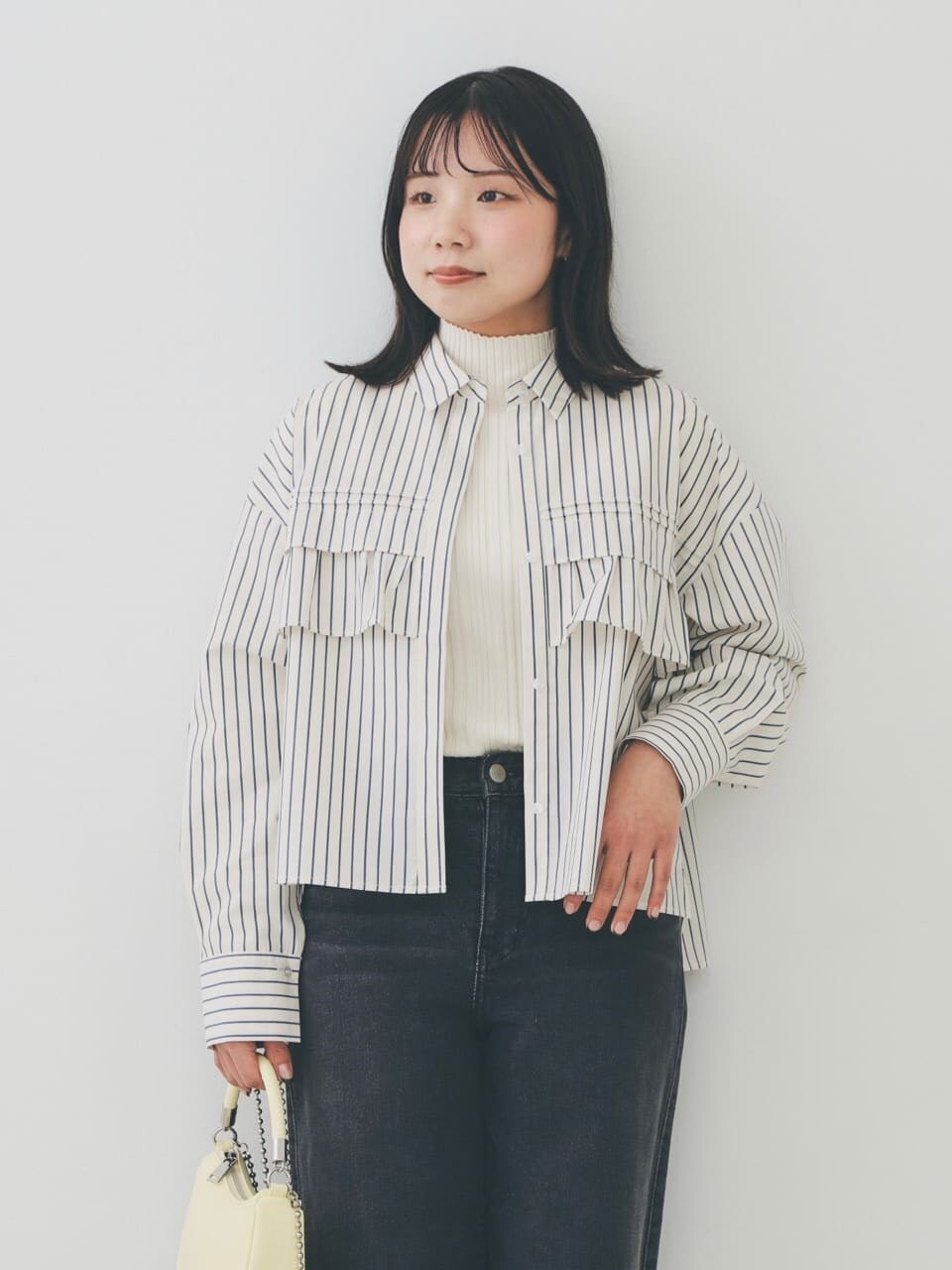 ベージュ系のシャツ/ブラウス、ホワイト系のニット/セーター、ブラック系のデニムパンツを着用したレディースの冬コーディネートの4枚目の写真
