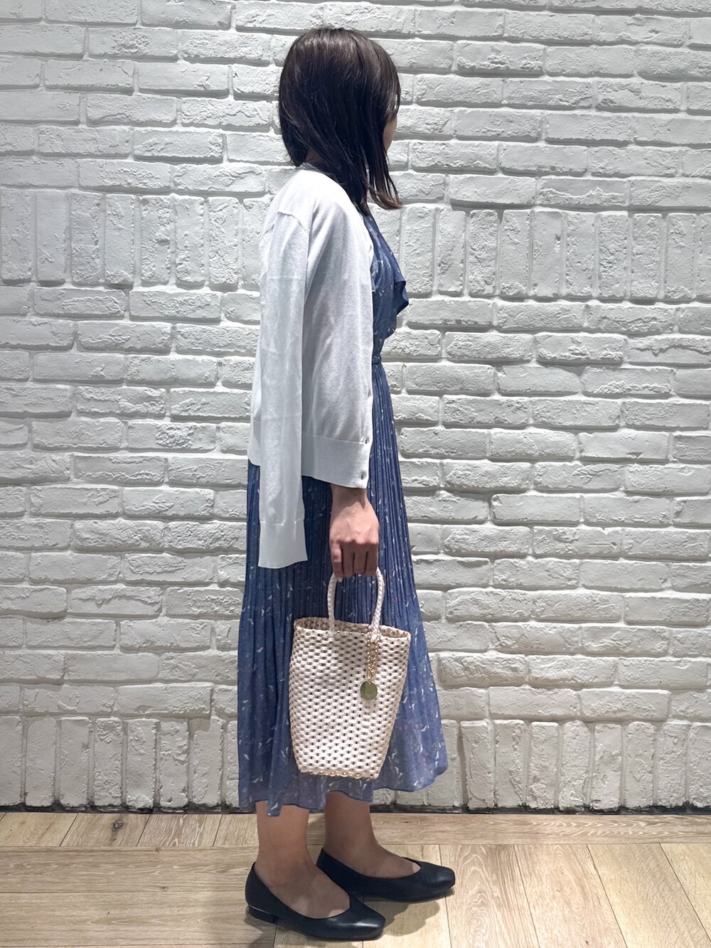 ブルー系のワンピース、ホワイト系のカーディガン/ボレロ、ゴールド系のトートバッグを着用したレディースの春コーディネートの2枚目の写真