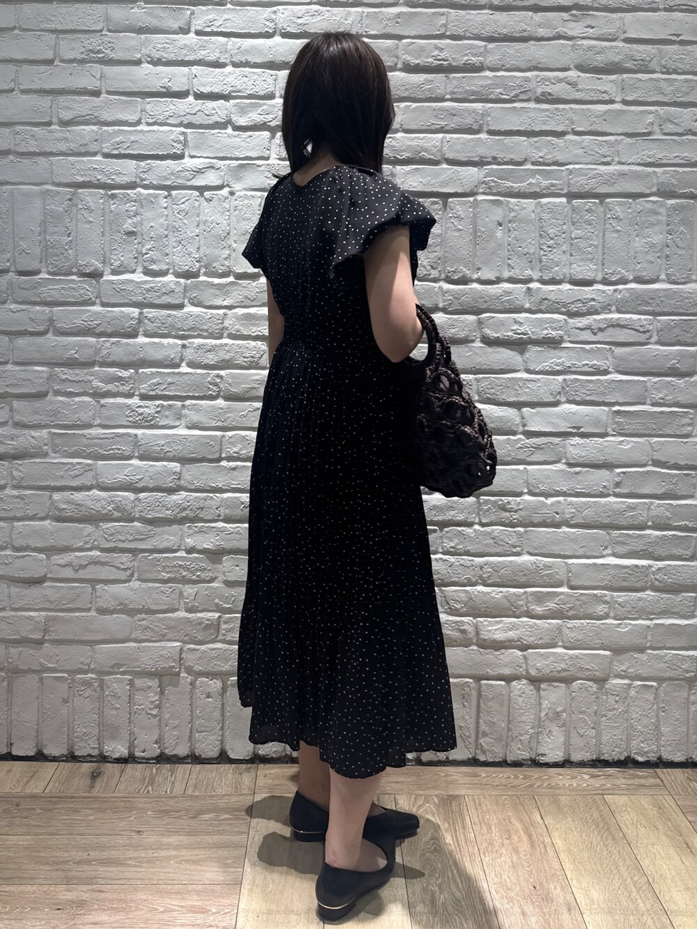 ブラック系のパンプス、ブラウン系のハンドバッグ、ブラック系のワンピースを着用したレディースの春コーディネートの2枚目の写真