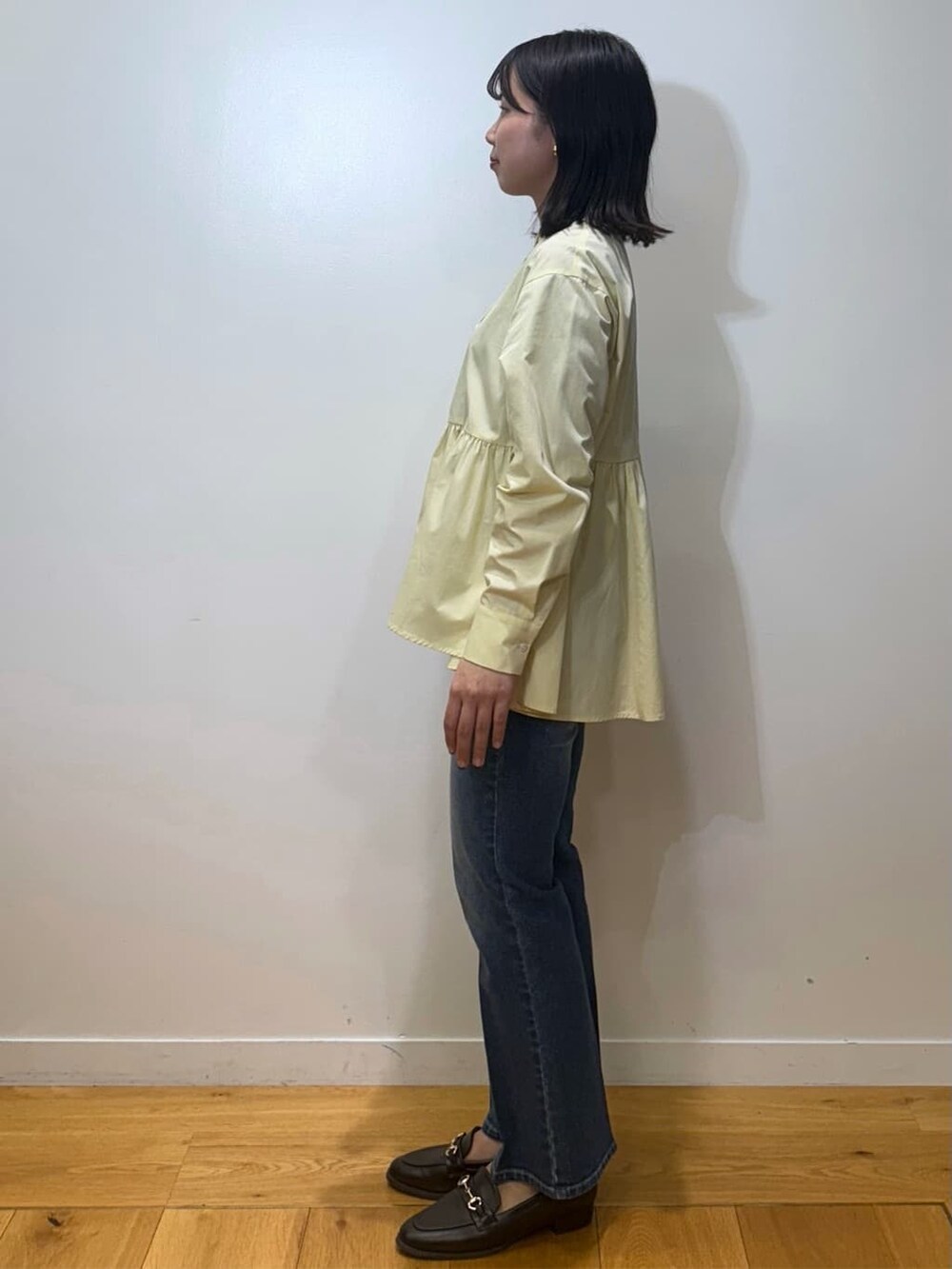 イエロー系のシャツ/ブラウス、ブルー系のデニムパンツ、ブラウン系のパンプスを着用したレディースの冬コーディネートの2枚目の写真