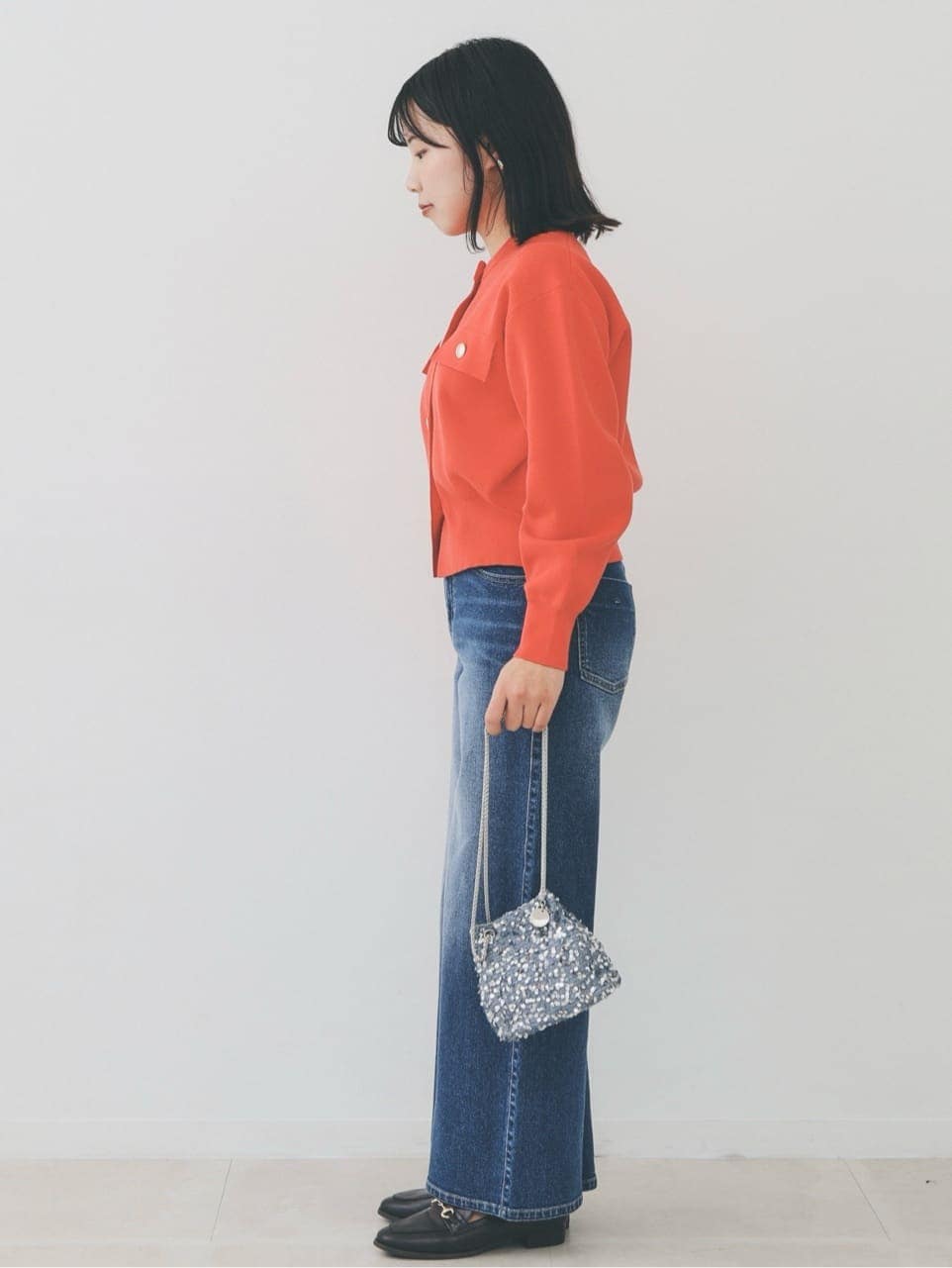 オレンジ系のカーディガン/ボレロ、ブルー系のデニムパンツ、グレー系のショルダーバッグを着用したレディースの冬コーディネートの3枚目の写真