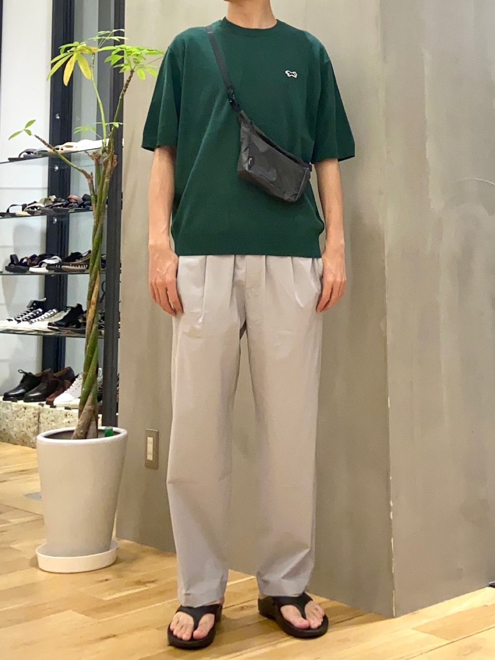 グリーン系のTシャツ/カットソー、グレー系のショルダーバッグ、ブラック系のサンダルを着用したメンズの春コーディネートの3枚目の写真